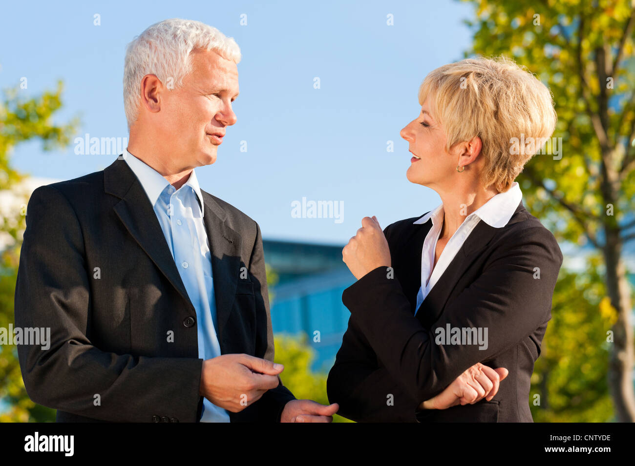 Business people - mature or senior - standing in a park outdoors talking Stock Photo