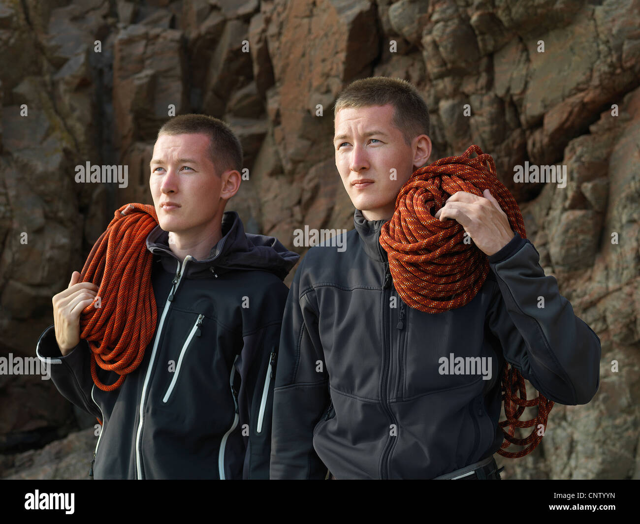 Men carrying loops of rope on beach Stock Photo