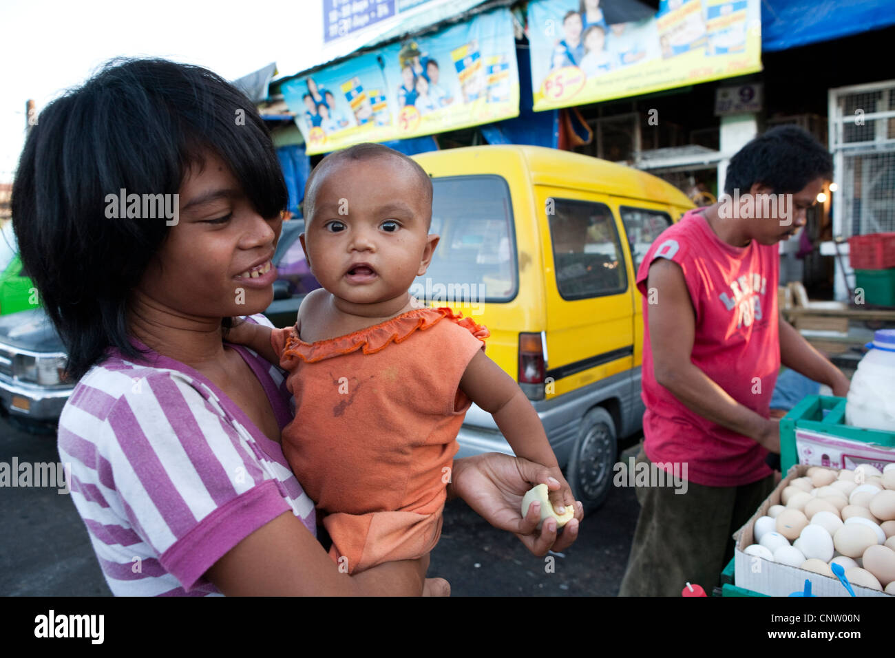 Woman with her baby, she is buying Balut, a fertilized duck embryo from a roadside vendor. Carbon Market, Cebu City, Philippines Stock Photo