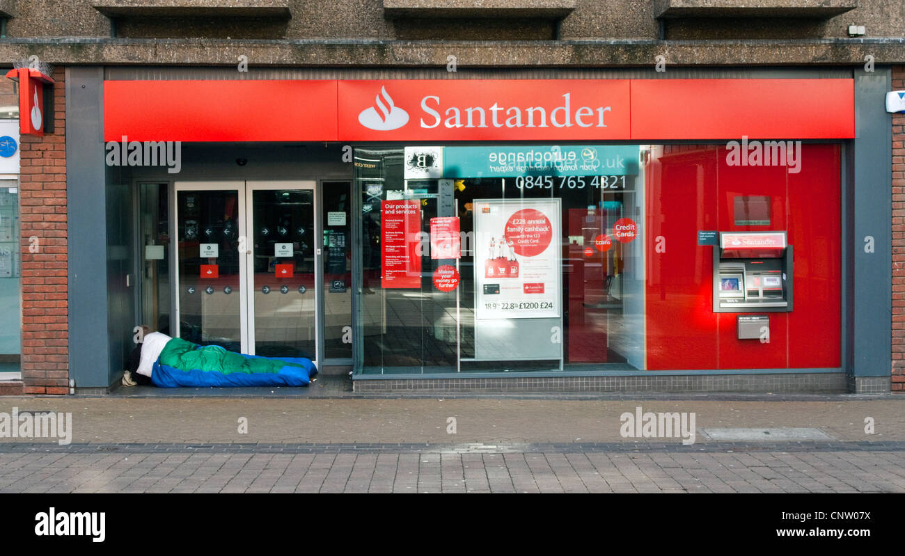 homeless man in sleeping bag outside Santander bank Stock Photo