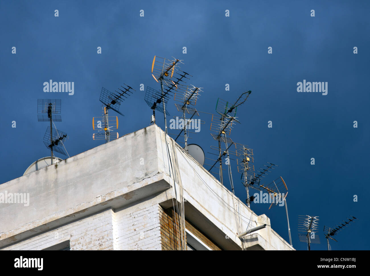 Television ariels on the roof of a building with dark blue sky Stock Photo