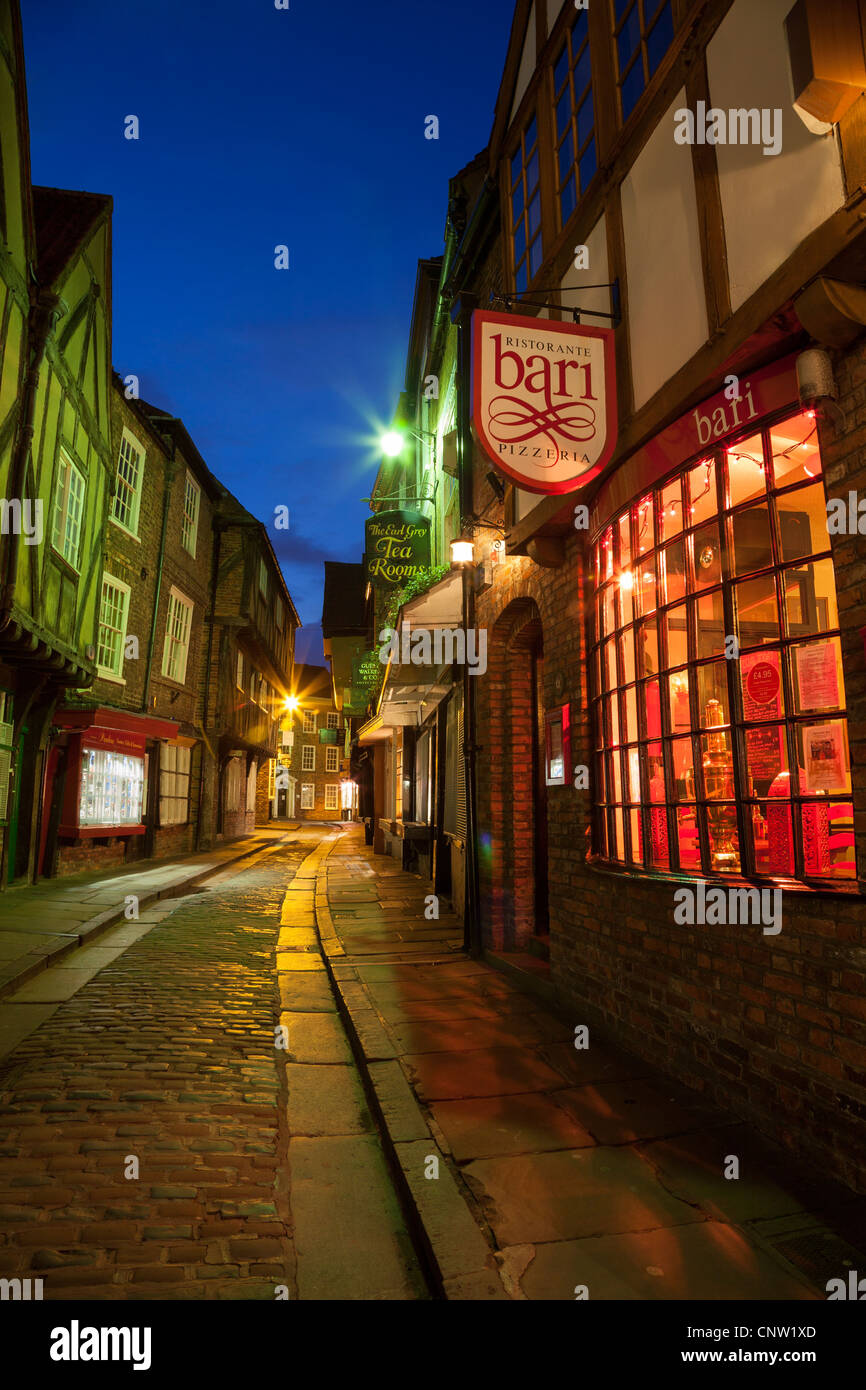 Colourful night shot of the Shambles showing over hanging buildings dating from the 14th century with  Bari Pizzaria foreground Stock Photo