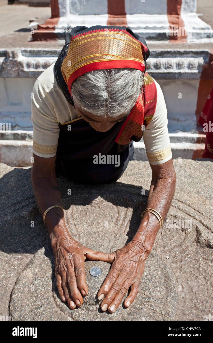 Indian woman touching a sacred stone (hindu ritual). Virupaksha temple. Hampi. India Stock Photo