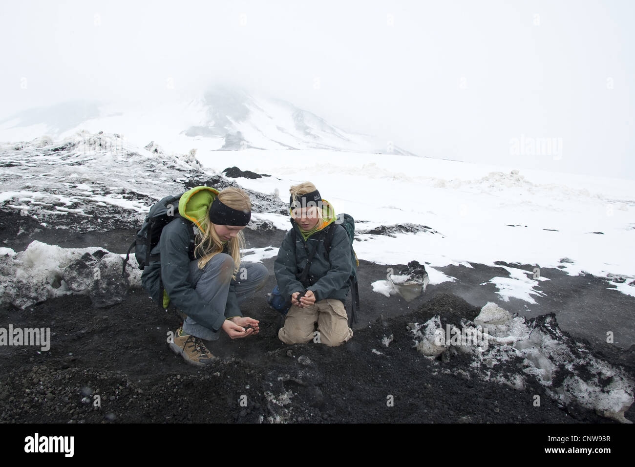 children warming their hands at warm lava from volcano Etna, Italy, Sicilia Stock Photo