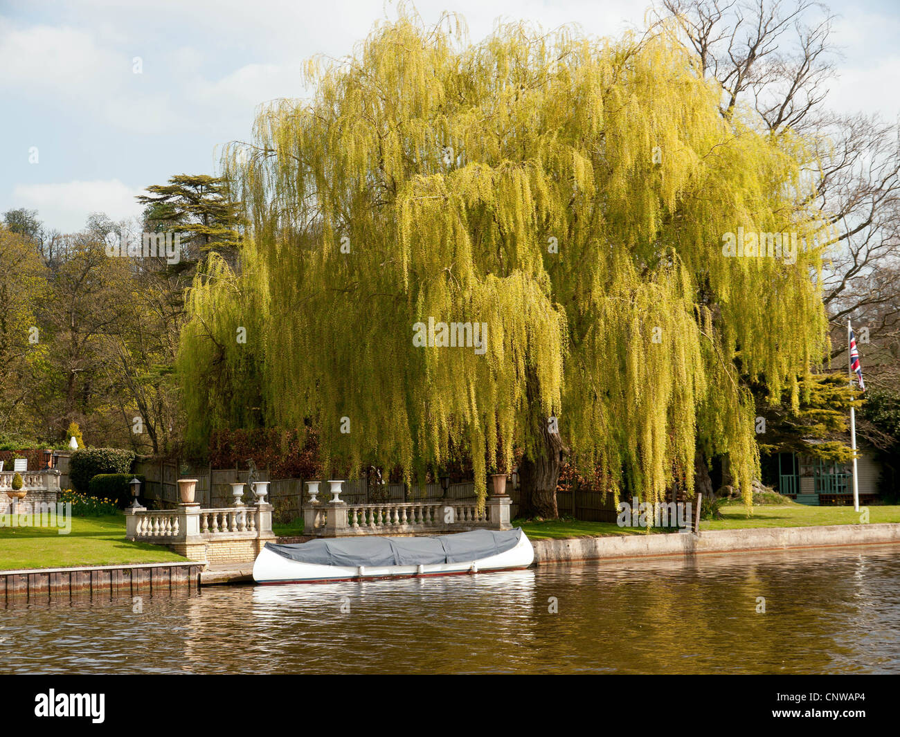 Picturesque waterside garden with moored boat by a weeping willow tree on the River Thames, Oxfordshire, UK Stock Photo