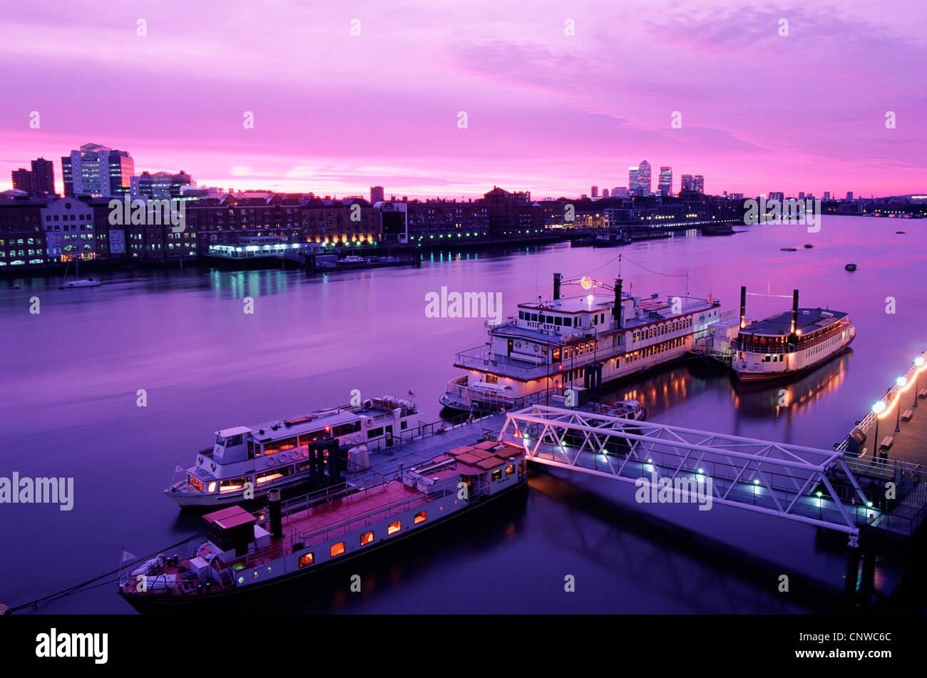 England, London, Night View of Boats on the Thames River with Docklands and Canary Wharf Skyline in Background Stock Photo