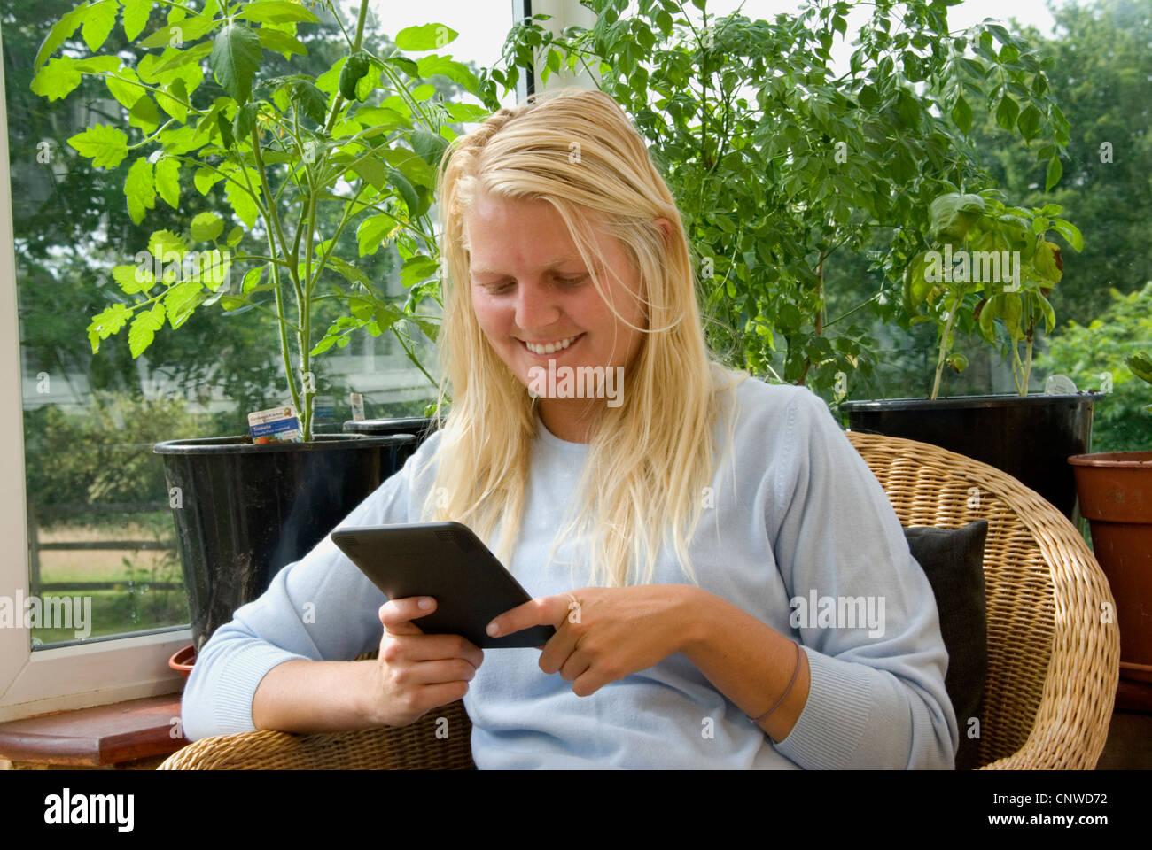 KIndle Amazon e-reader electronic reader girl young woman reading on Kindle;  Hayley Williamson MR Stock Photo