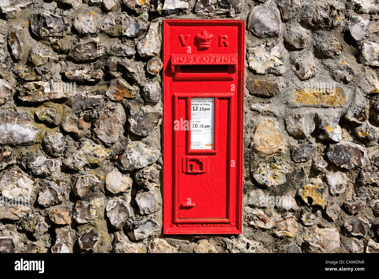 British Red Victorian Mail box embedded in a flint stone wall Stock Photo