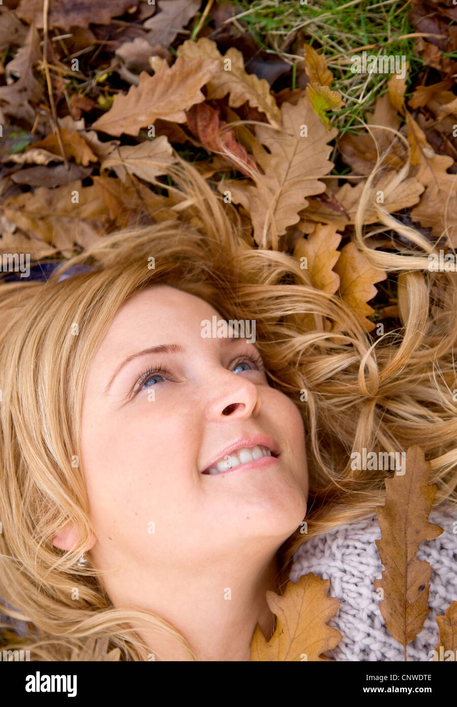 young woman lying in autumn foliage, smiling Stock Photo - Alamy