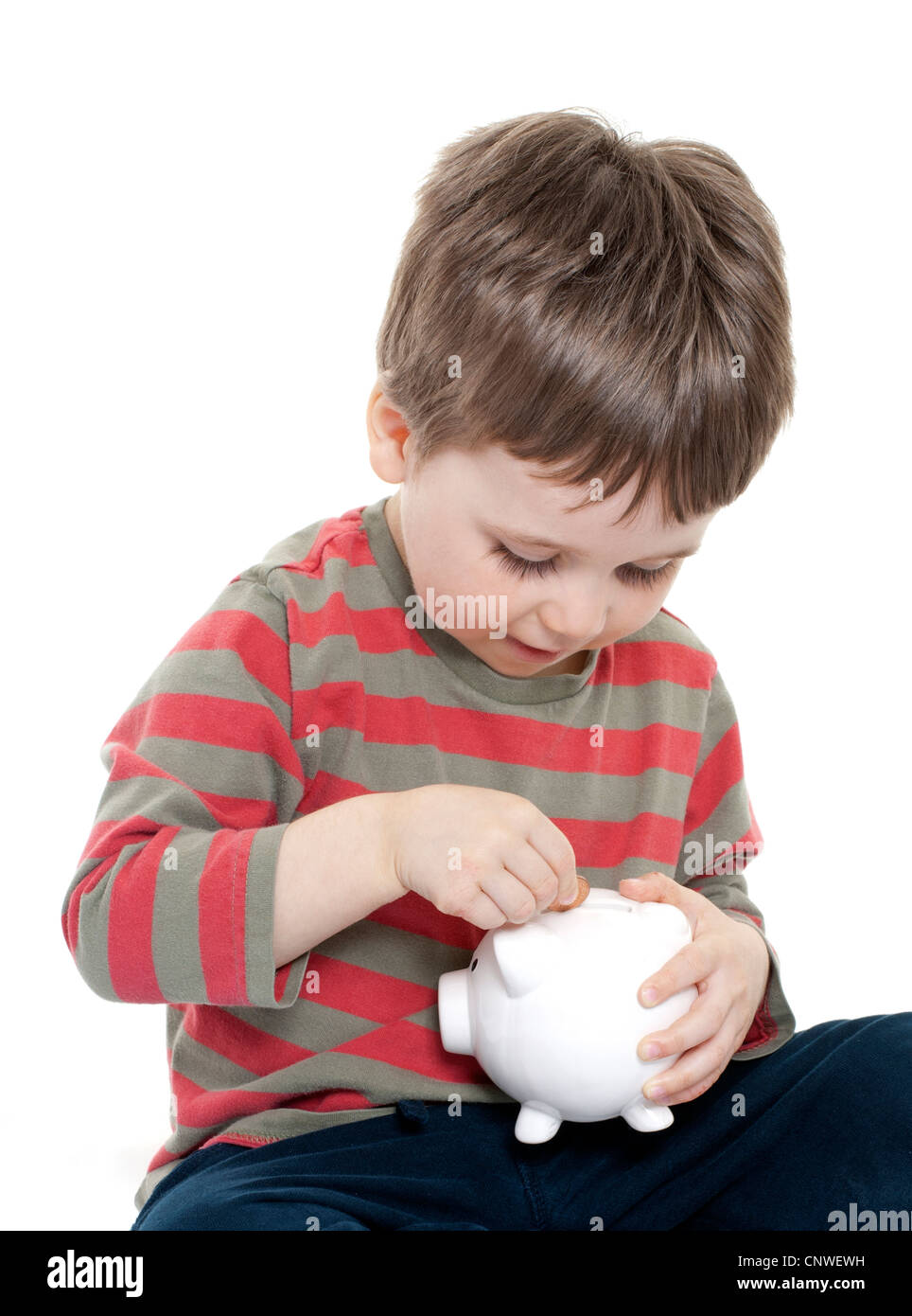 Boy putting money in piggy bank Stock Photo - Alamy
