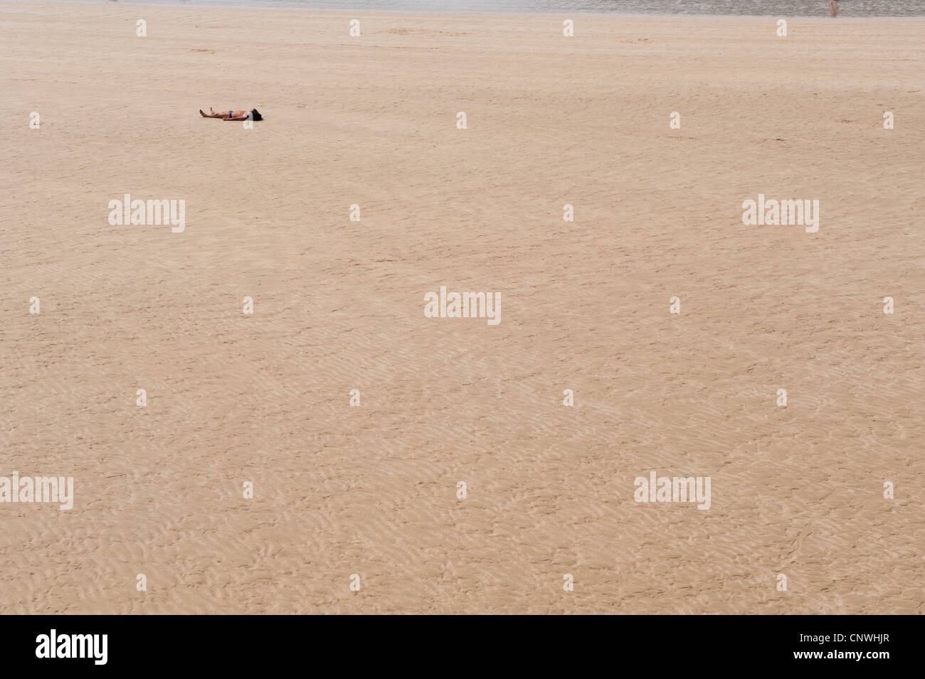 lone sun bather on an empty beach Stock Photo