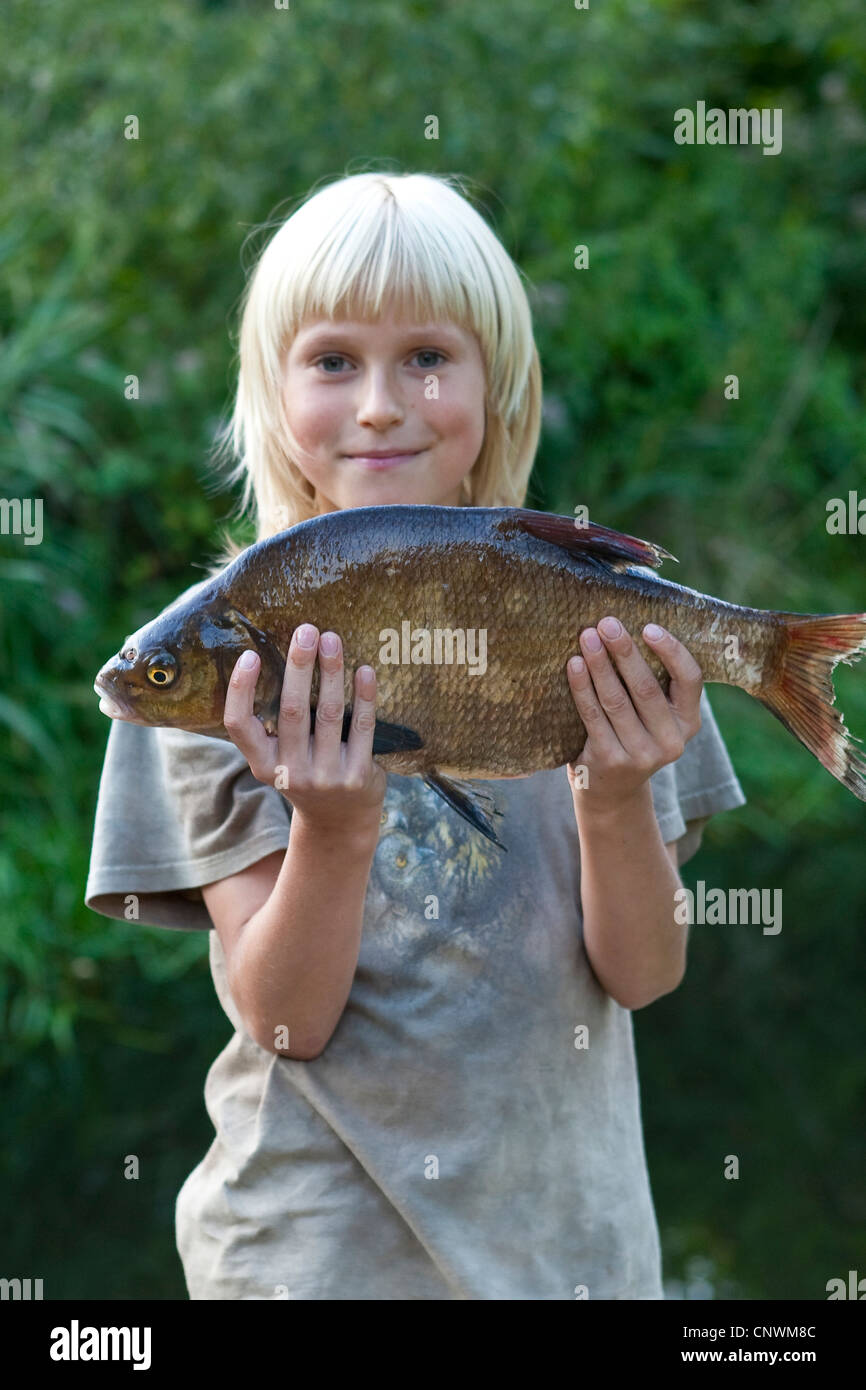 common bream, freshwater bream, carp bream (Abramis brama), boy proudly presenting a caught fish Stock Photo