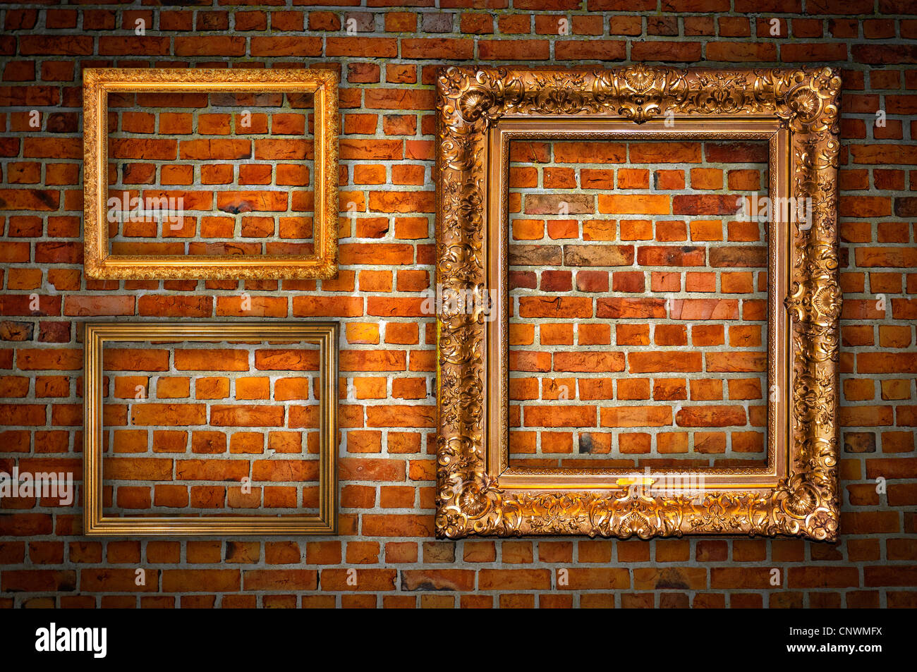 Old ornate golden frames hanging on a brick wall. Stock Photo