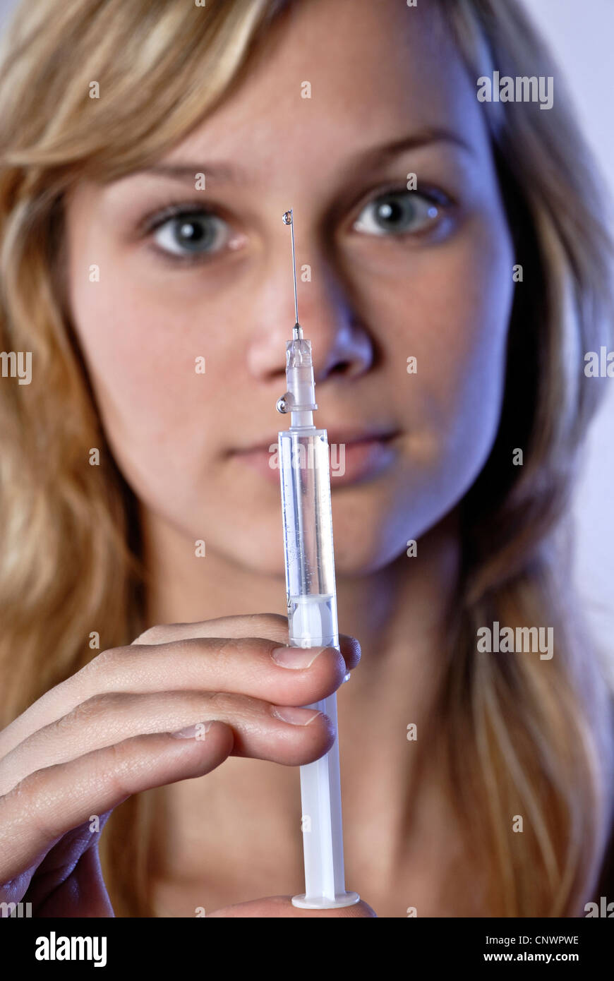Young woman with blond hair with a syringe as a symbol for drug addiction. Stock Photo