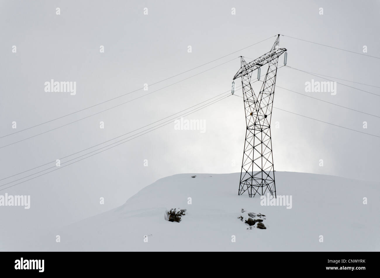A pylon and power lines in silhouette on a snowy hill Stock Photo - Alamy
