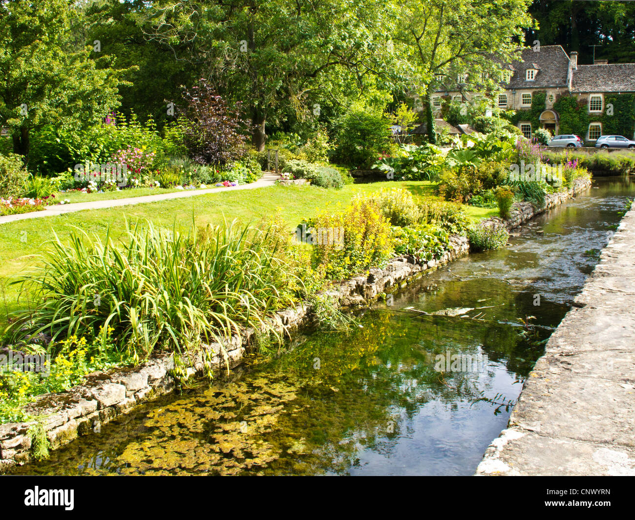 View to Bibury Trout Farm in the pretty English Cotswold village of Bibury in Gloucestershire England UK.Swan Hotel in distance. Stock Photo