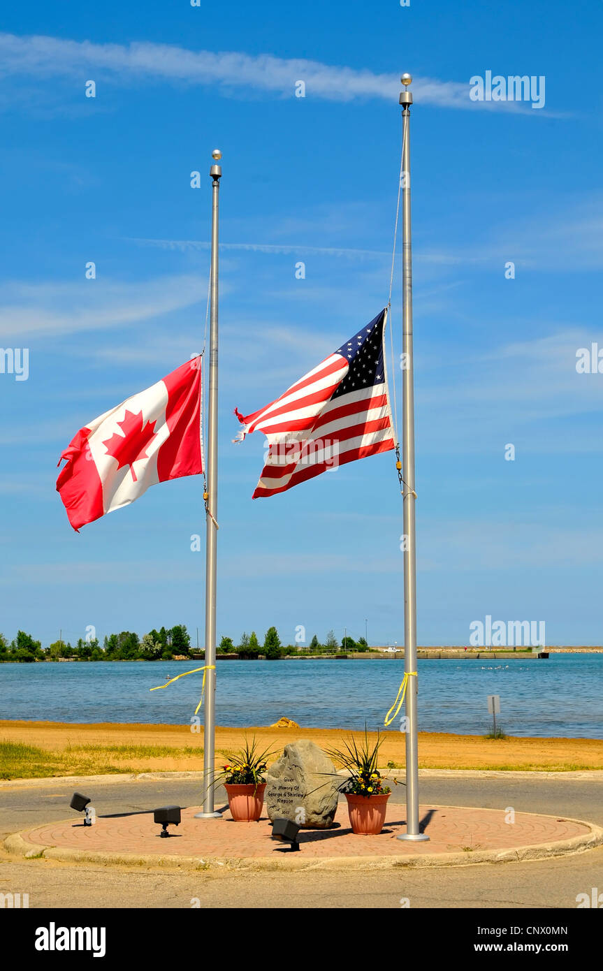 American and Canadian flags fly together at half mast staff Stock Photo