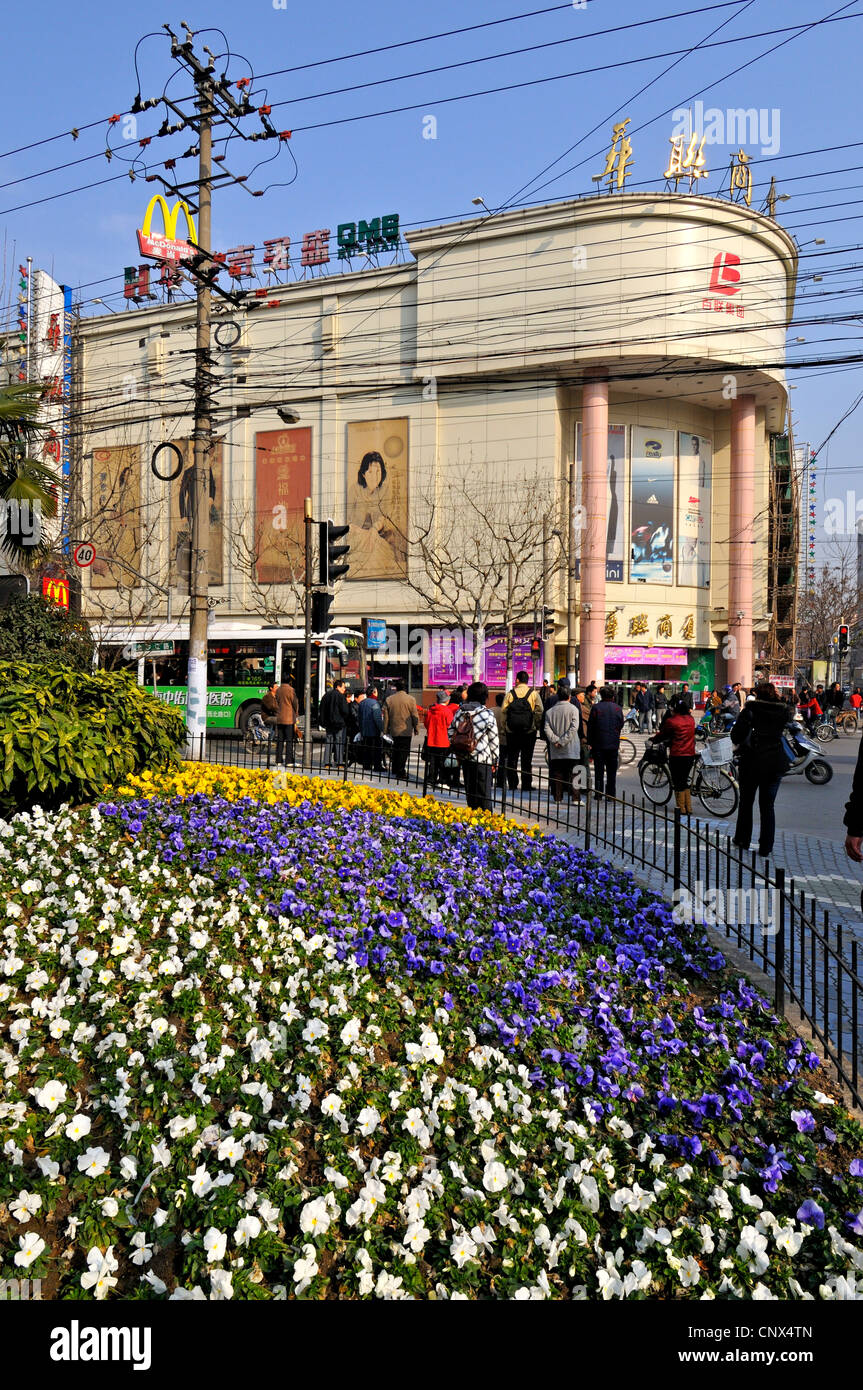 Spring flowers in municipal flowerbeds, modern shops and crowded electricity powerlines in suburban Shanghai, China. Stock Photo