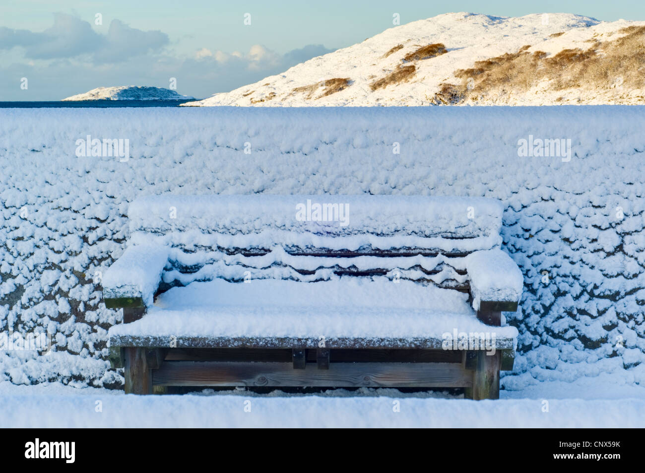 Snowy bench on harbour wall, Lochinver village, Sutherland, Scottish Highlands in winter Stock Photo