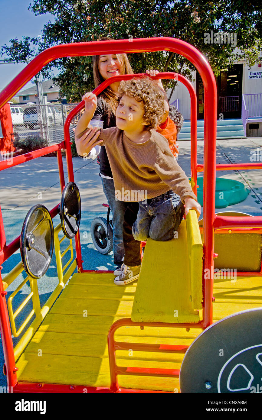 A female staff member helps a blind and crippled child use the playground at the Blind Children's Learning Center Stock Photo