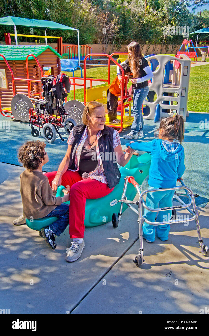 Young and old staff members help blind and crippled children use the playground at the Blind Children's Learning Center. Stock Photo