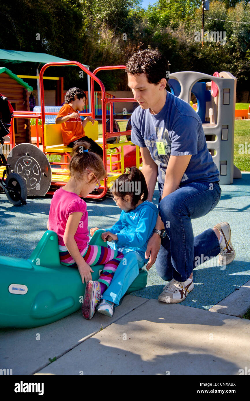 A young staff member helps blind and crippled children use the playground at the Blind Children's Learning Center. Stock Photo