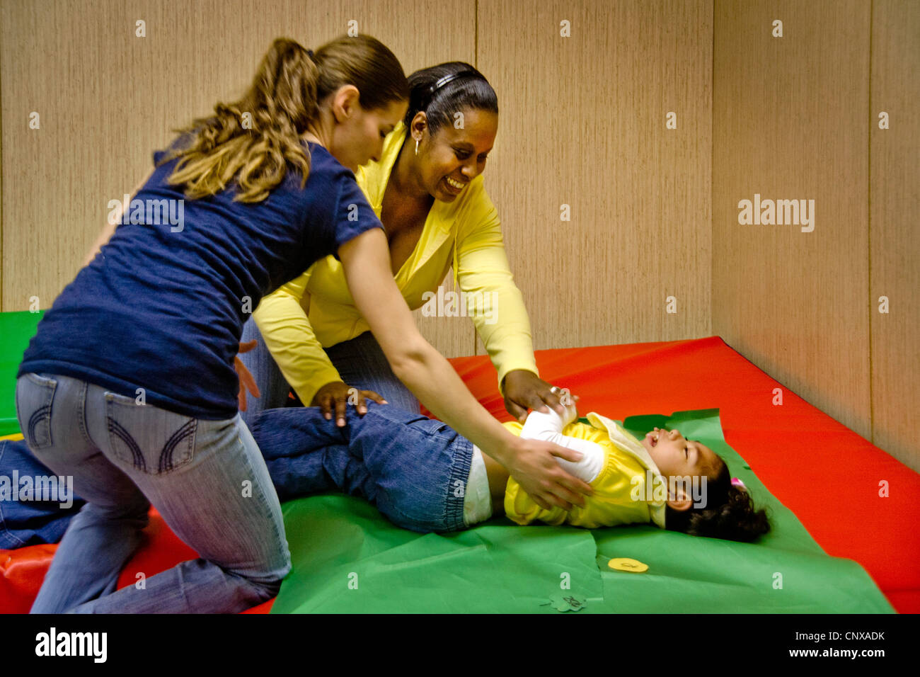 Teachers encourage a vision-impaired girl during a treasure hunt in a sensory motor group at  Blind Children's Learning Center. Stock Photo