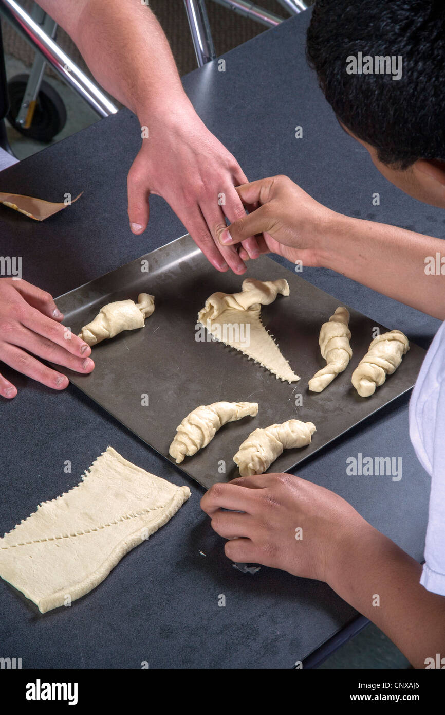 A teacher helps a handicapped visionimpaired teenager make rolls by