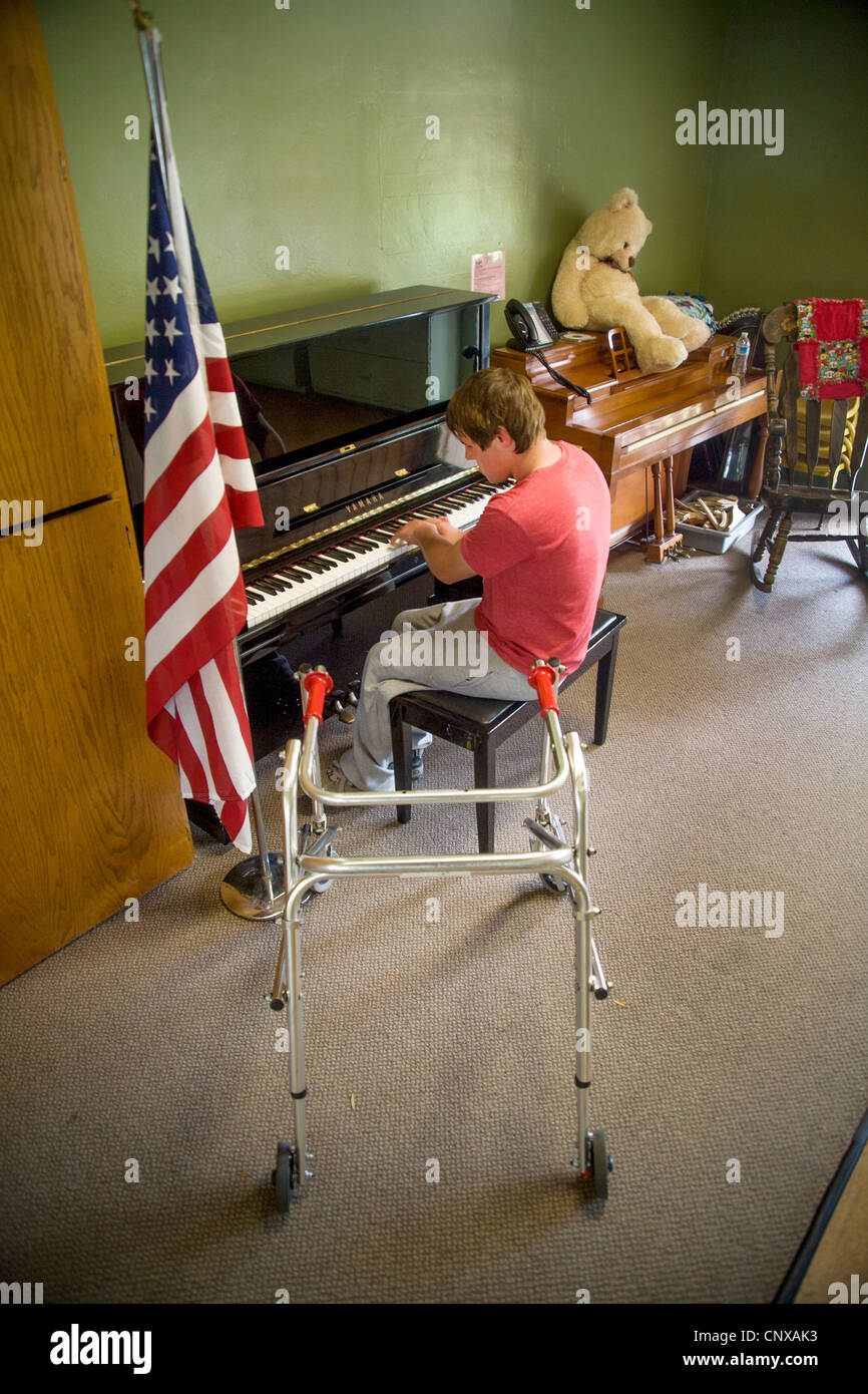A blind and handicapped teen boy plays piano at the Blind Children's