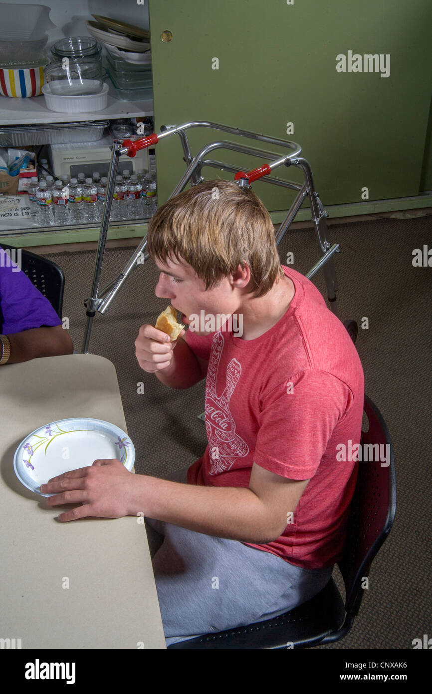 A blind and handicapped teen boy samples food from a baking and cooking class at the Blind Children's Learning Center in Santa A Stock Photo