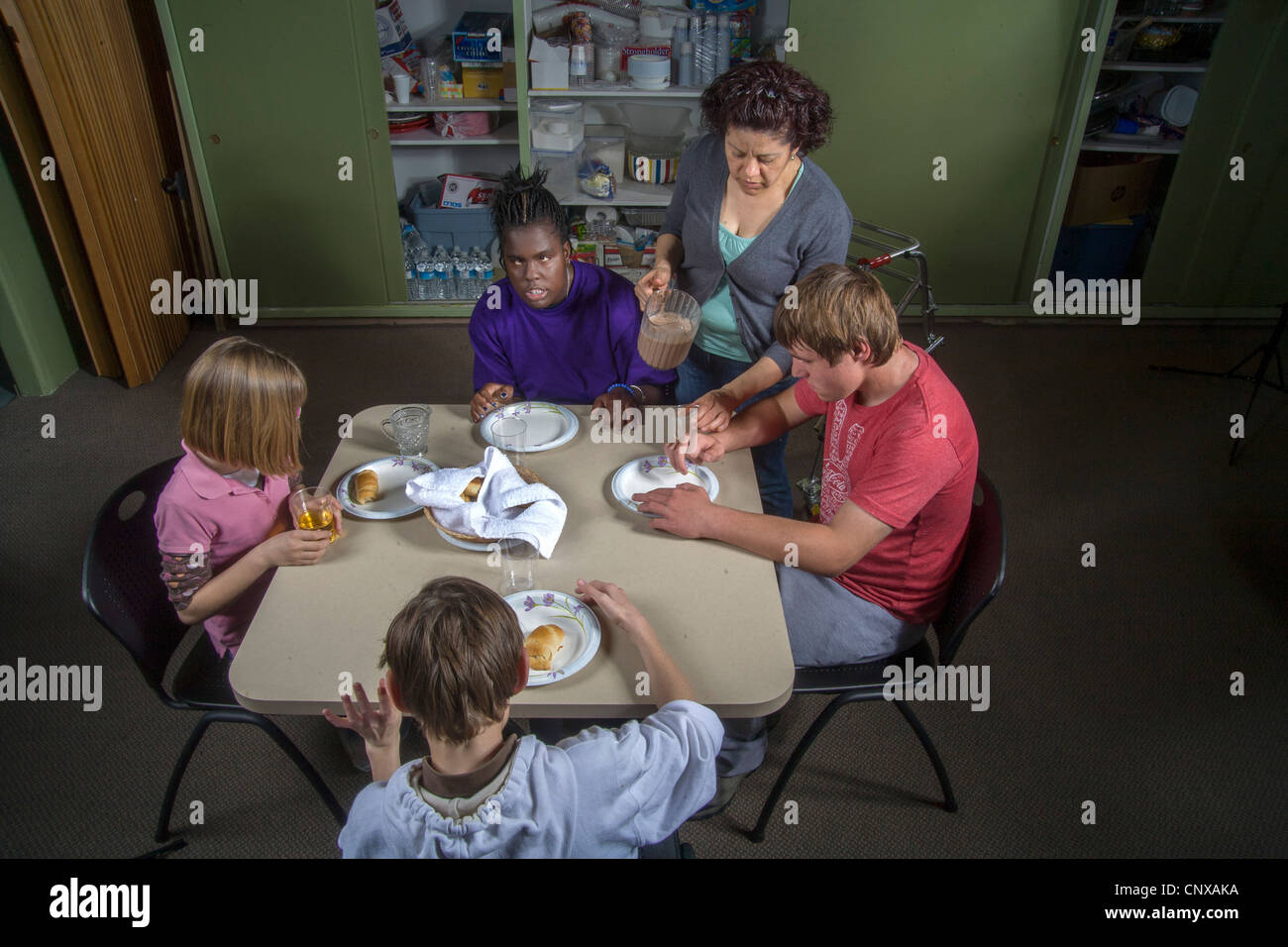 A teacher joins her blind and handicapped students sampling food they made in a cooking class at the Blind Children's Center. Stock Photo