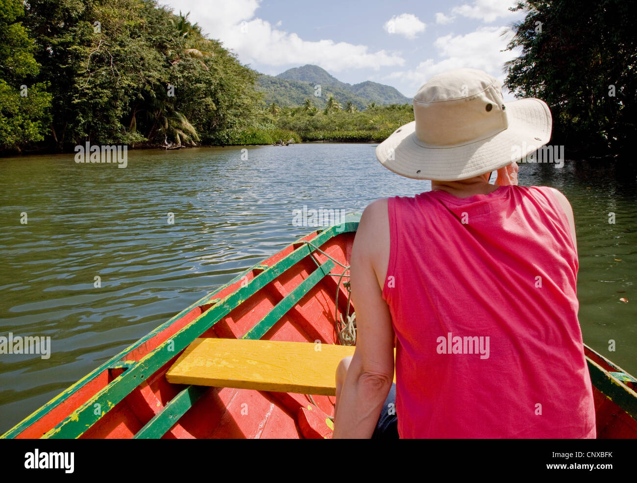 A woman passenger enjoys the view as she is rowed up the Indian River in Dominica Stock Photo