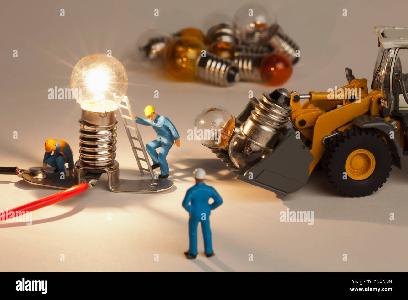 Miniature electrician figurines working on an illuminated light bulb Stock Photo Alamy