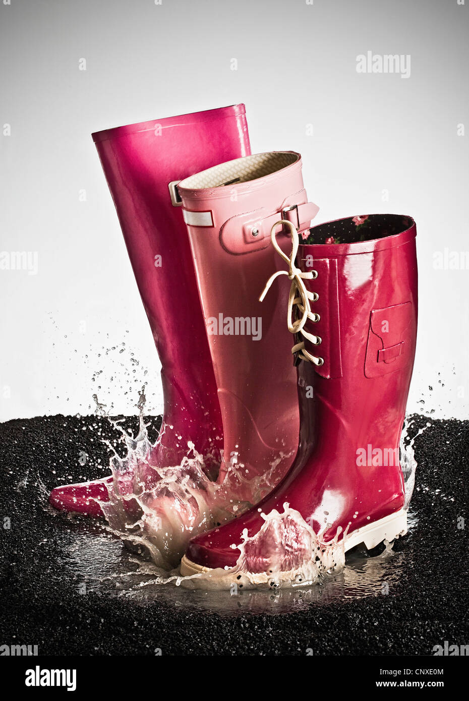 Three pink rubber boots splashing in a puddle Stock Photo Alamy