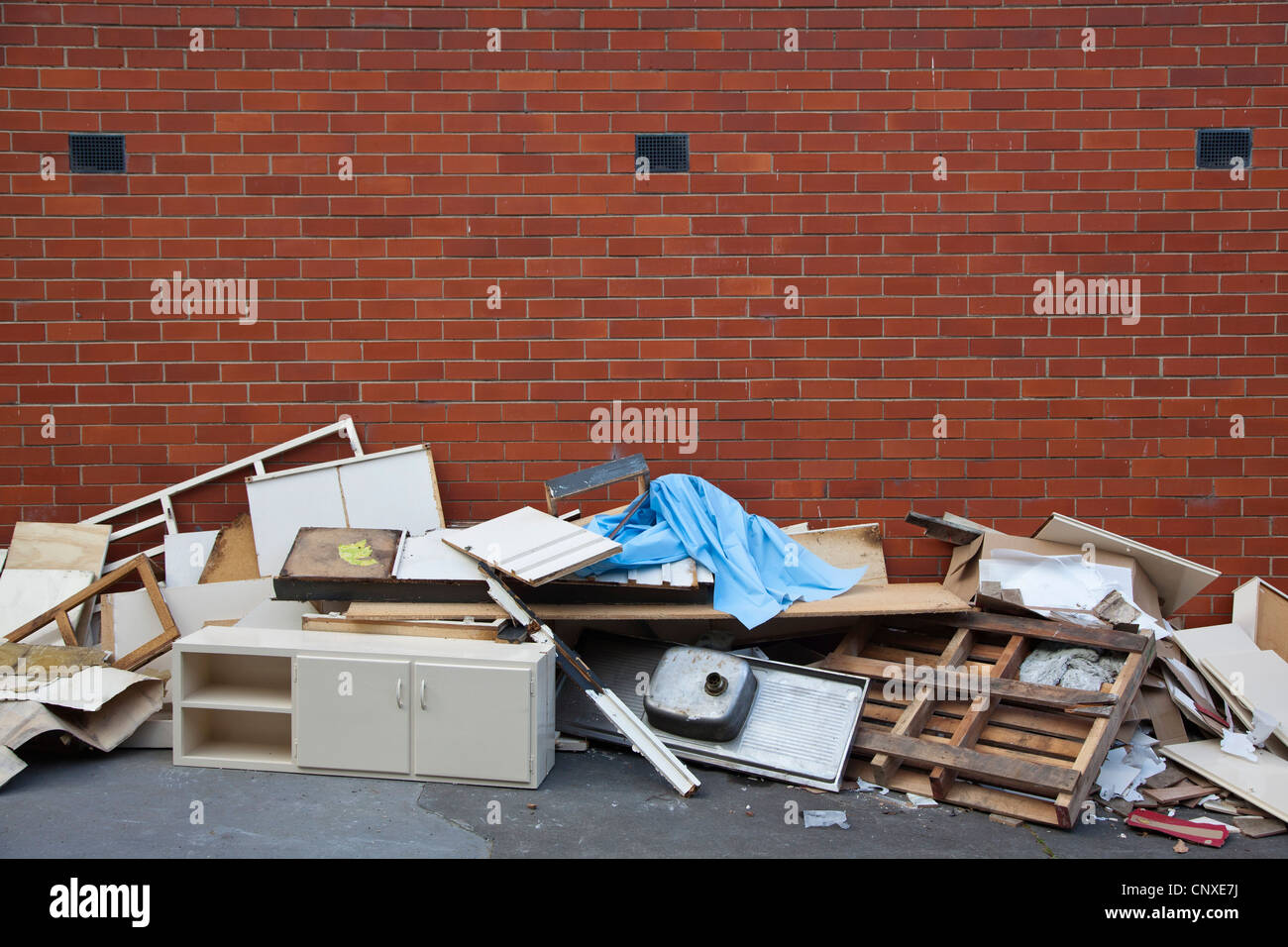 Broken furniture and scraps of garbage piled up against a brick wall Stock Photo Alamy