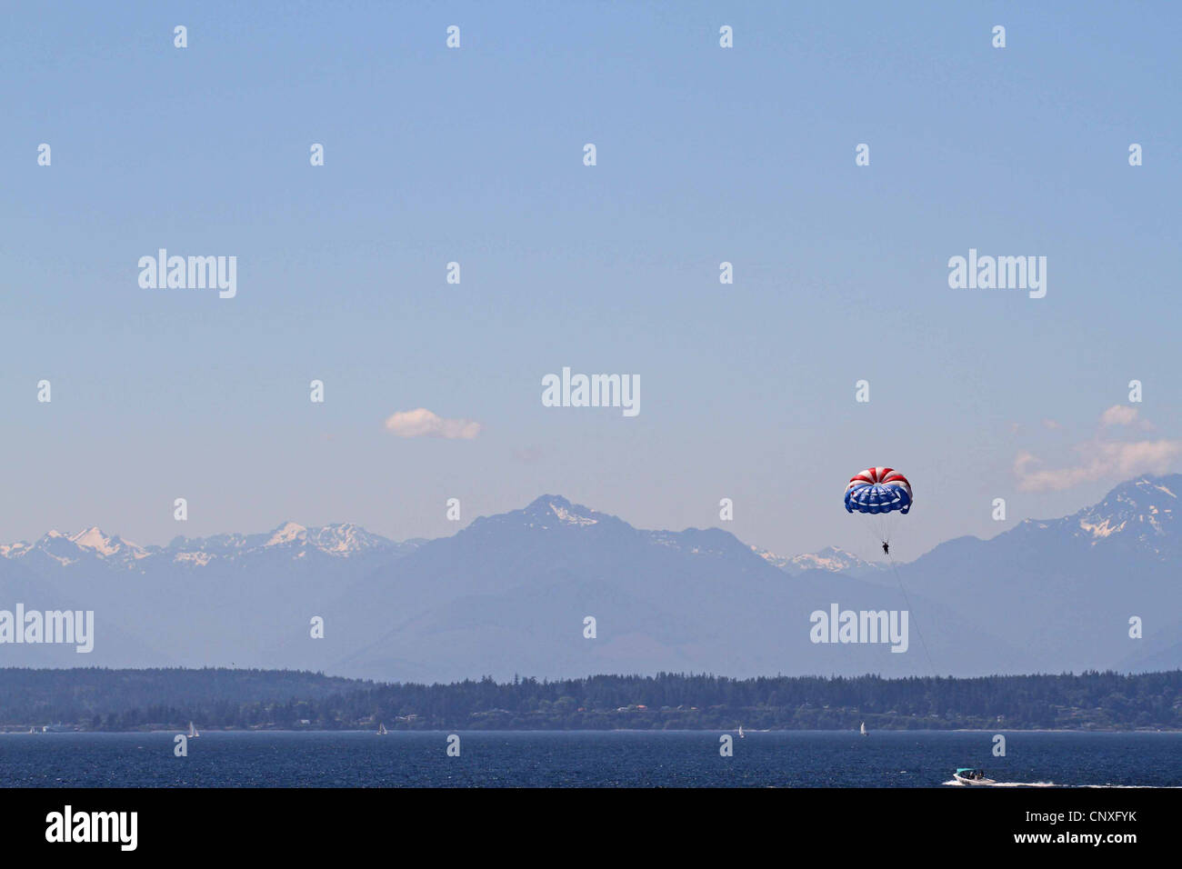Parasailing in Seattle,  USA, with a view of the Rocky Mountains in the distance Stock Photo