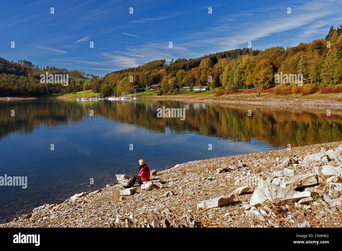 woman sitting at the lakefront of Henne storage lake and enjoying a good view, Germany, North Rhine-Westphalia, Sauerland, Meschede Stock Photo