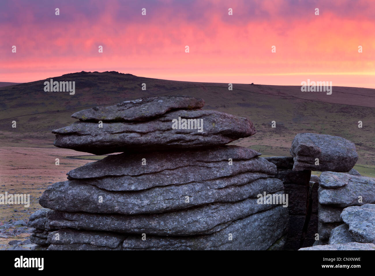Colourful dawn sky above Great Mis Tor, viewed from the granite outcrops of Great Staple Tor, Dartmoor, Devon, England. Stock Photo
