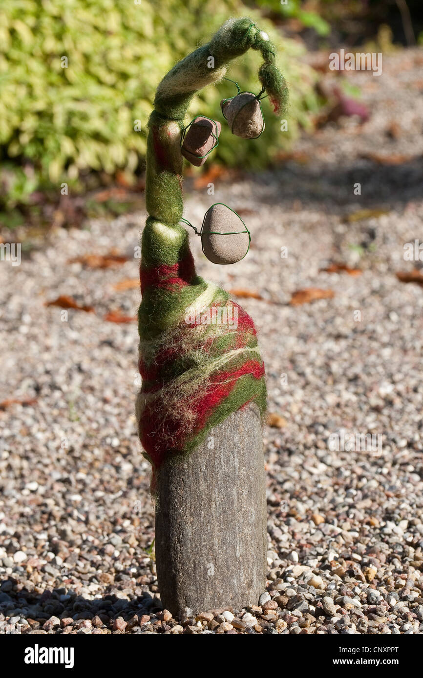 'felt stone troll' serving as garden decoration: natural stone equipped with caps of felted wool is standing on shingle ground, Germany Stock Photo