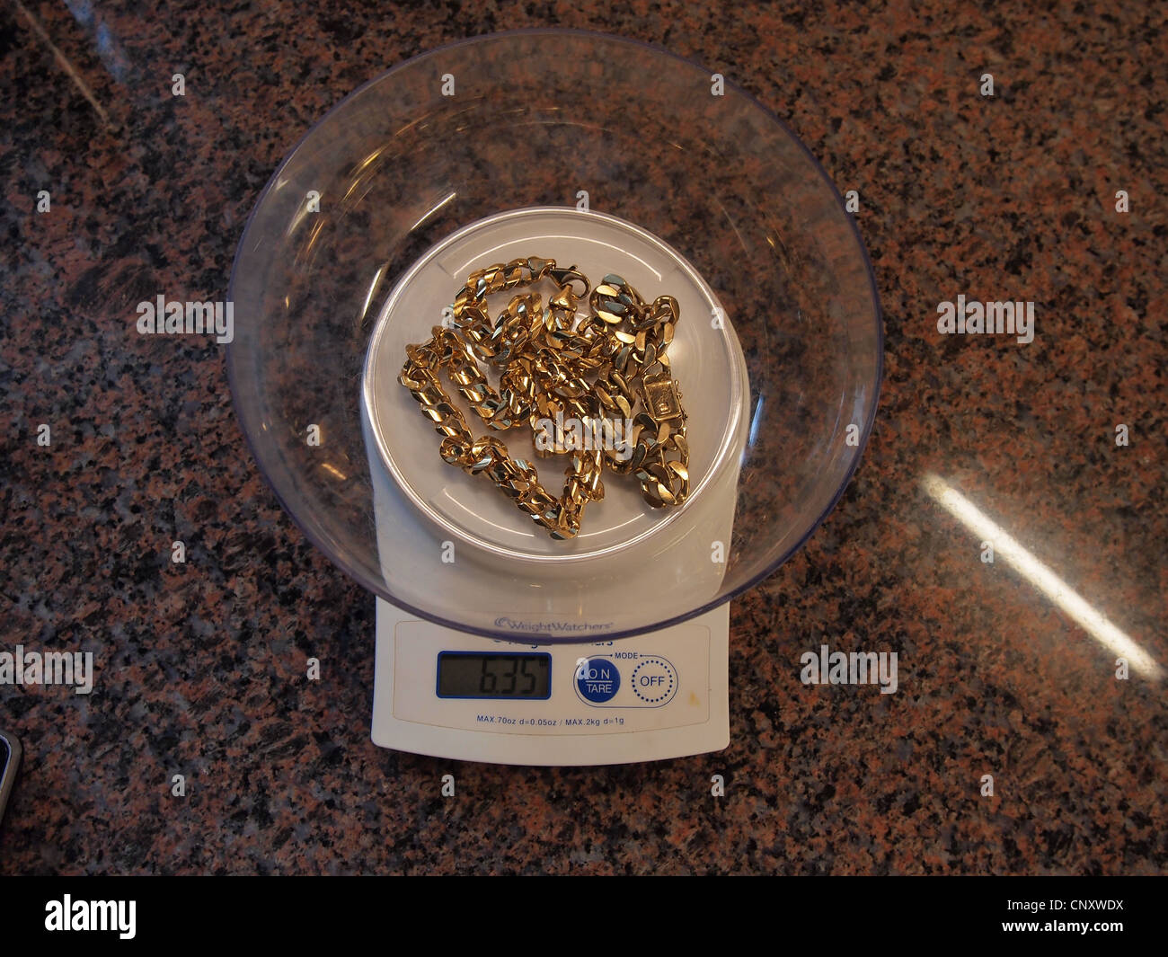 A gold necklace being weighed on a food 