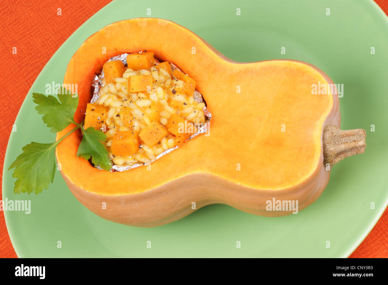 Half pumpkin filled with pumpkin risotto served on a green plate Stock Photo