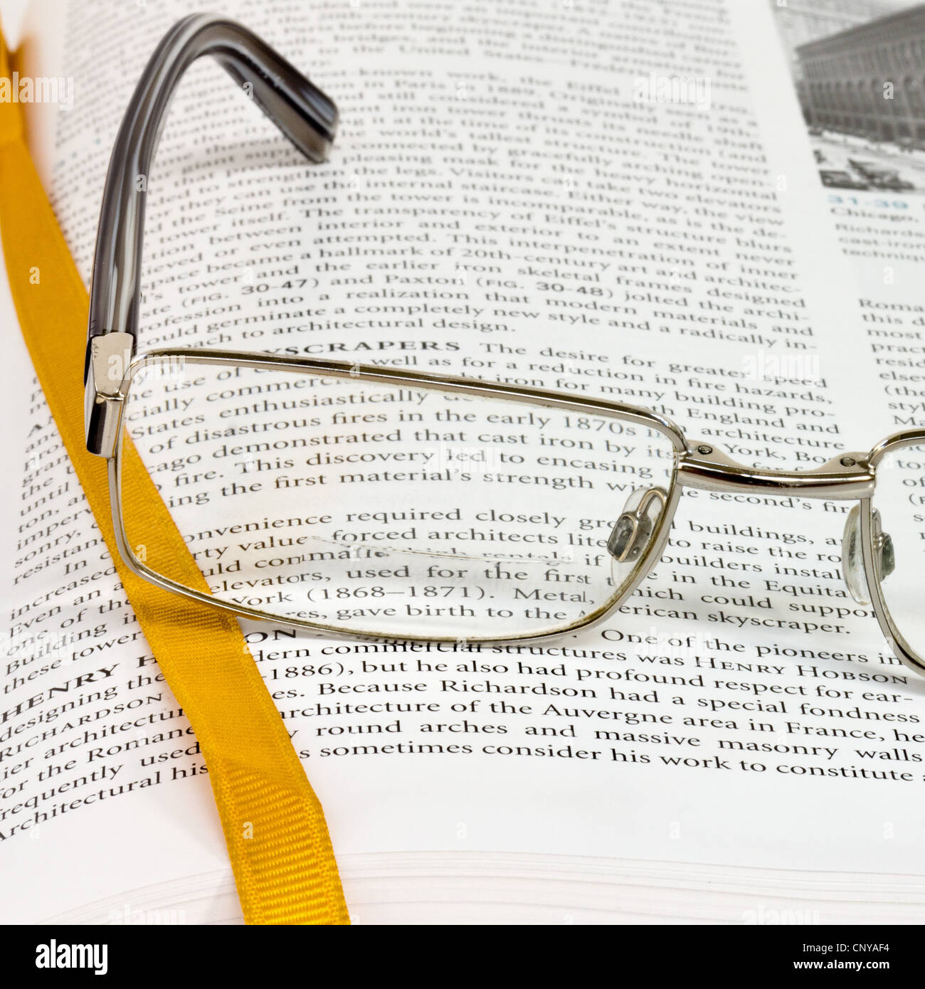 Close up of spectacles on textbook with gold ribbon bookmark Stock Photo