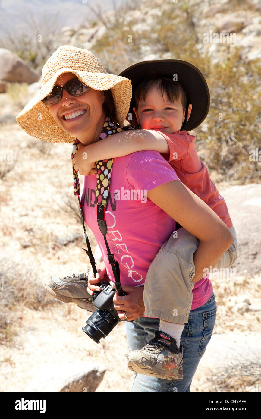 Mother giving young son a piggyback ride while hiking in the Anza Borrego desert, California. (MR) Stock Photo