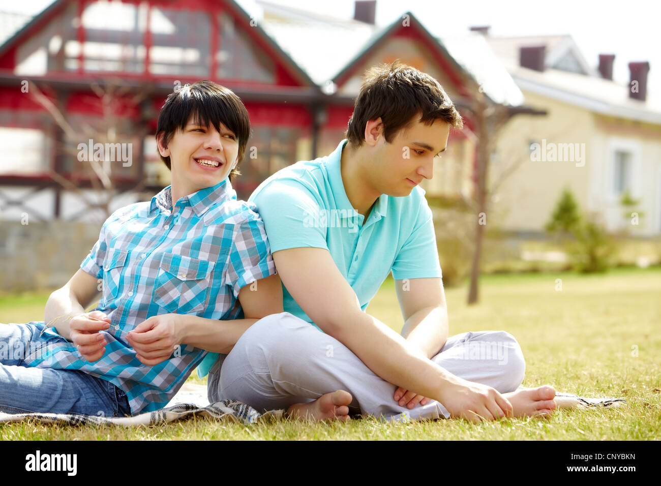 Young gays sitting together on the lawn enjoying warm weather Stock Photo