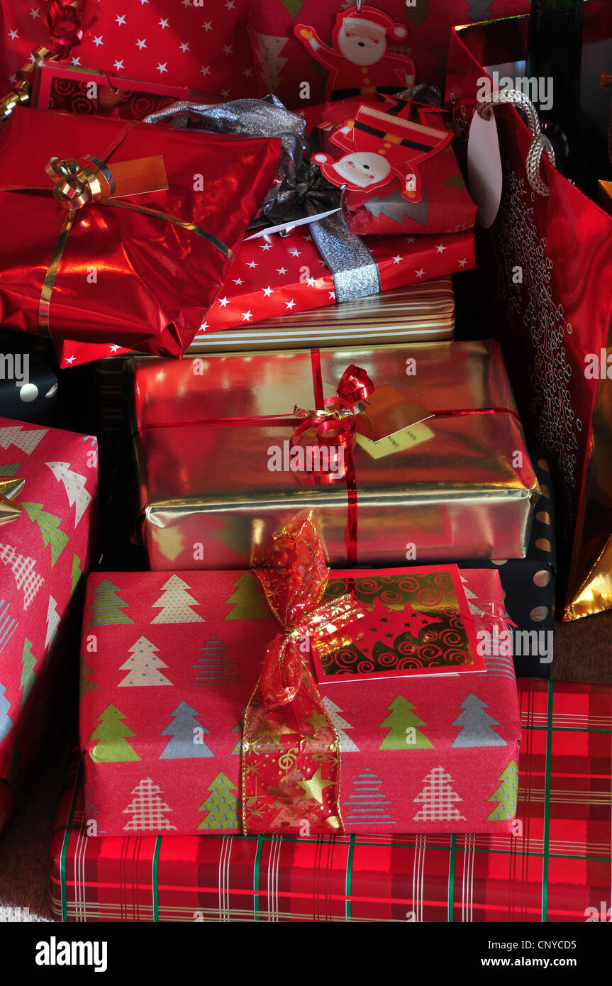 A mass of Christmas presents wrapped in red and gold paper with ribbons ...
