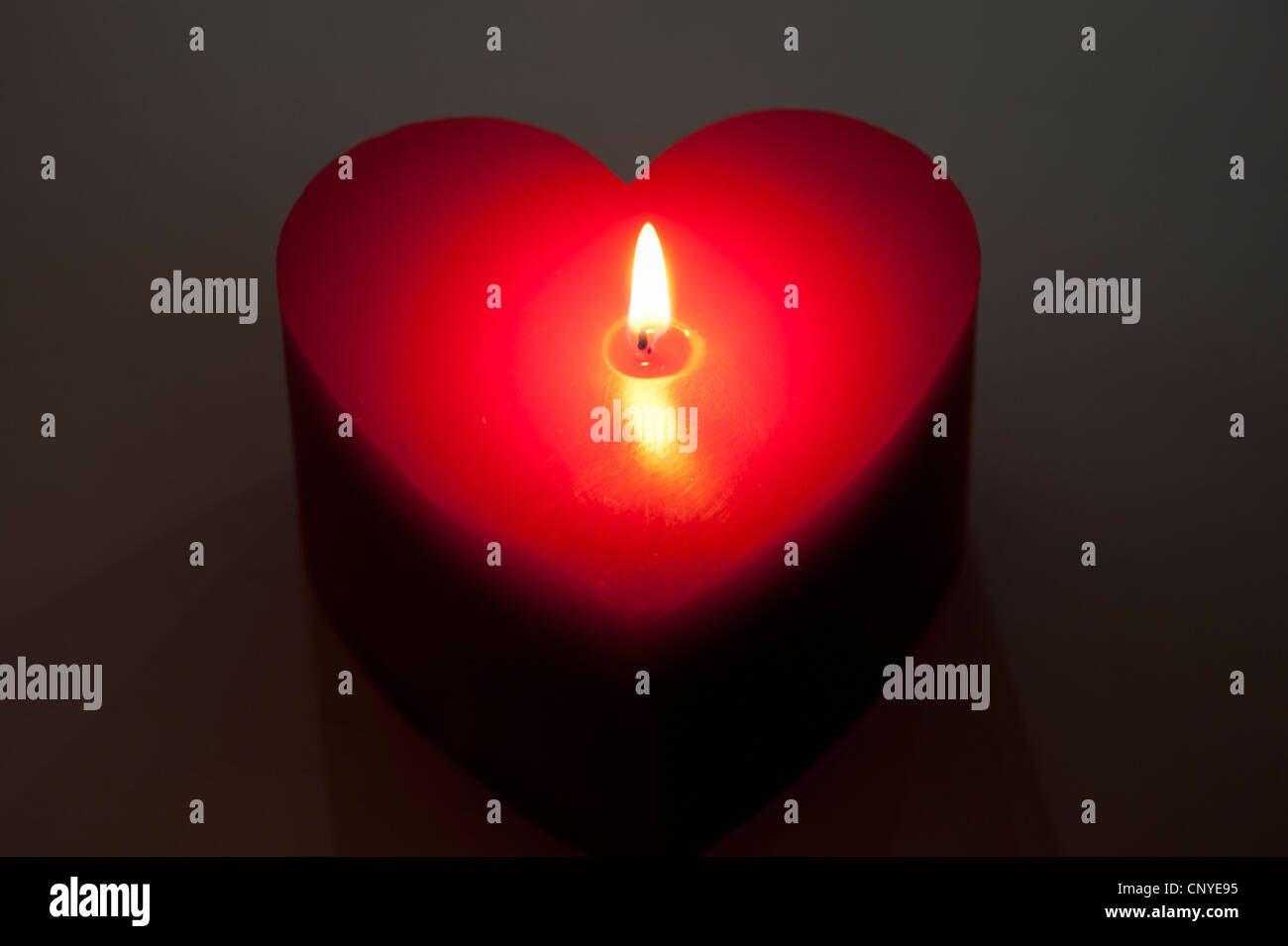 A red heart shaped candle, lit Stock Photo Alamy