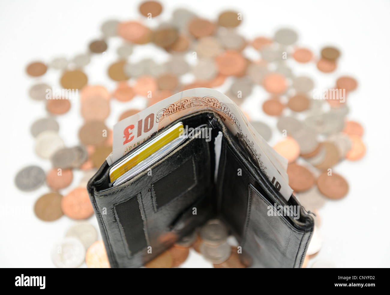 a wallet with a british 10 pound note and coins in the background Stock