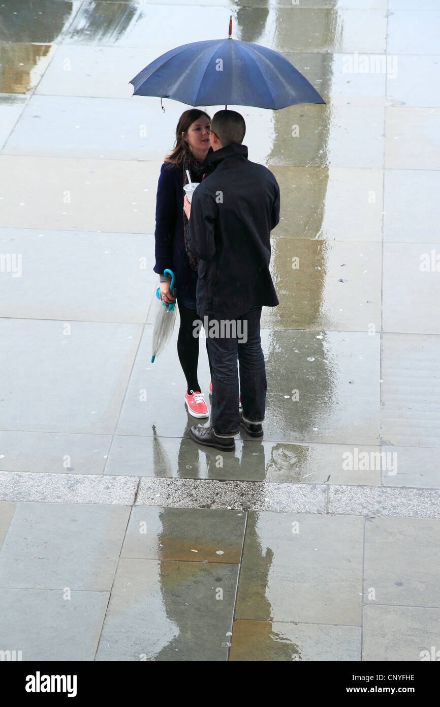 Young couple standing under umbrella in the rain, London, UK Stock ...