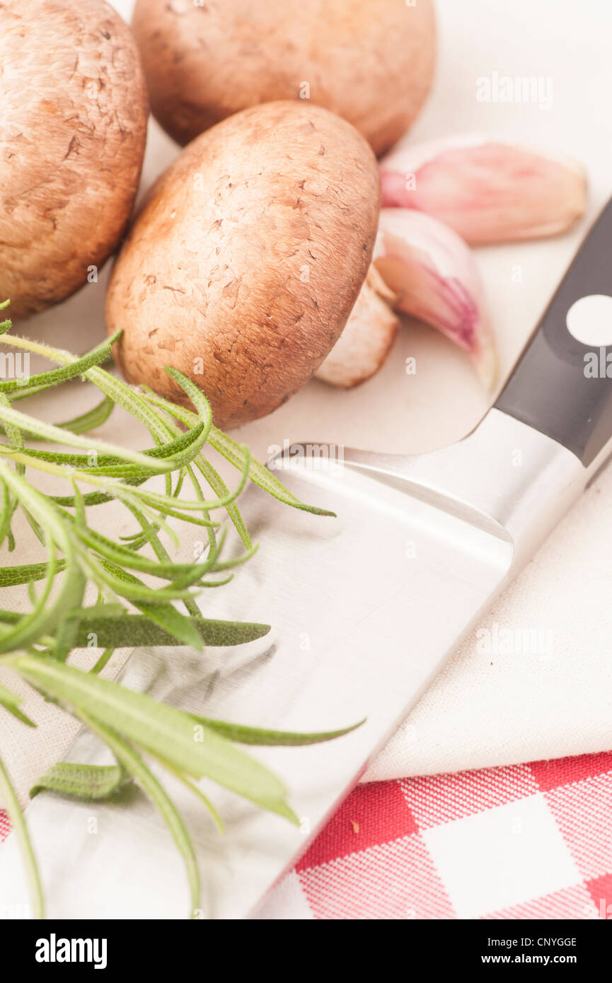 Chestnut mushrooms, Rosemary and kitchen knife on a cutting board Stock Photo