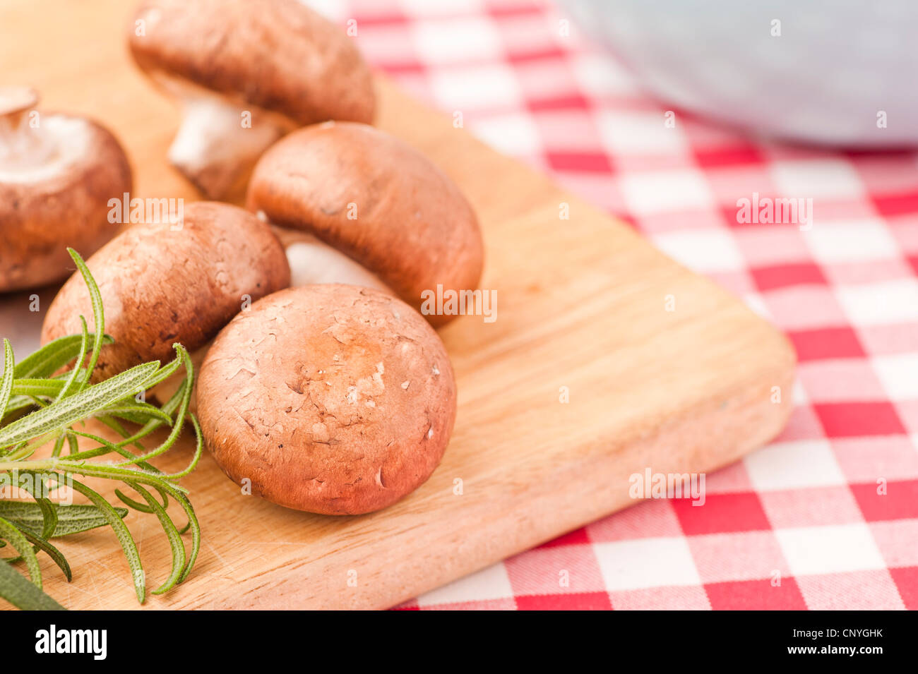 Chestnut mushrooms and Rosemary on a cutting board Stock Photo